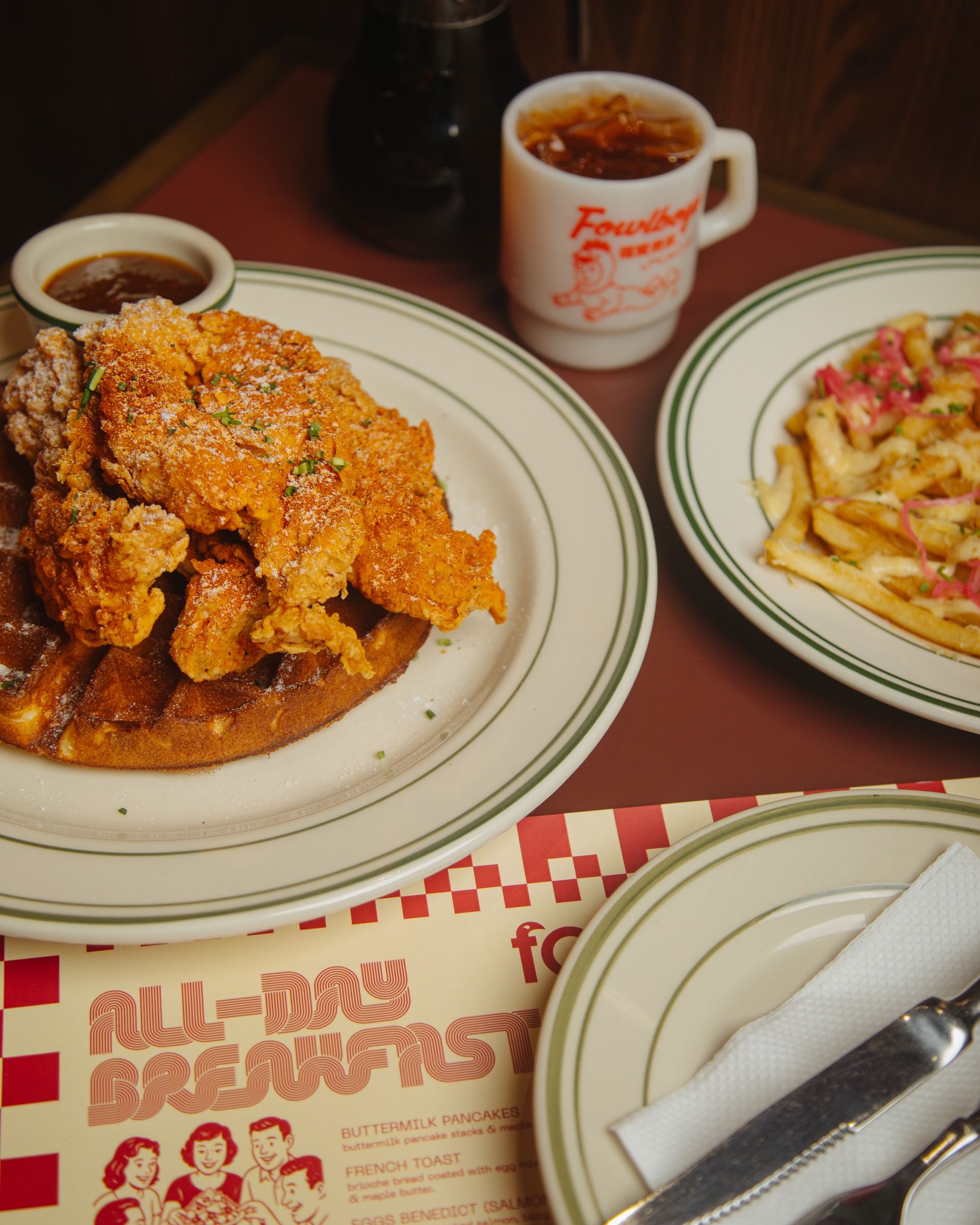 Chicken and waffle on a diner plate with fries and a mug, on the all-day breakfast placemat