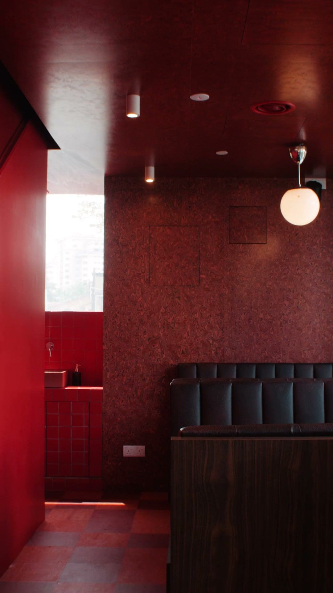 Inside The MET: a dark leather booth against a red burl wall under a globe lamp