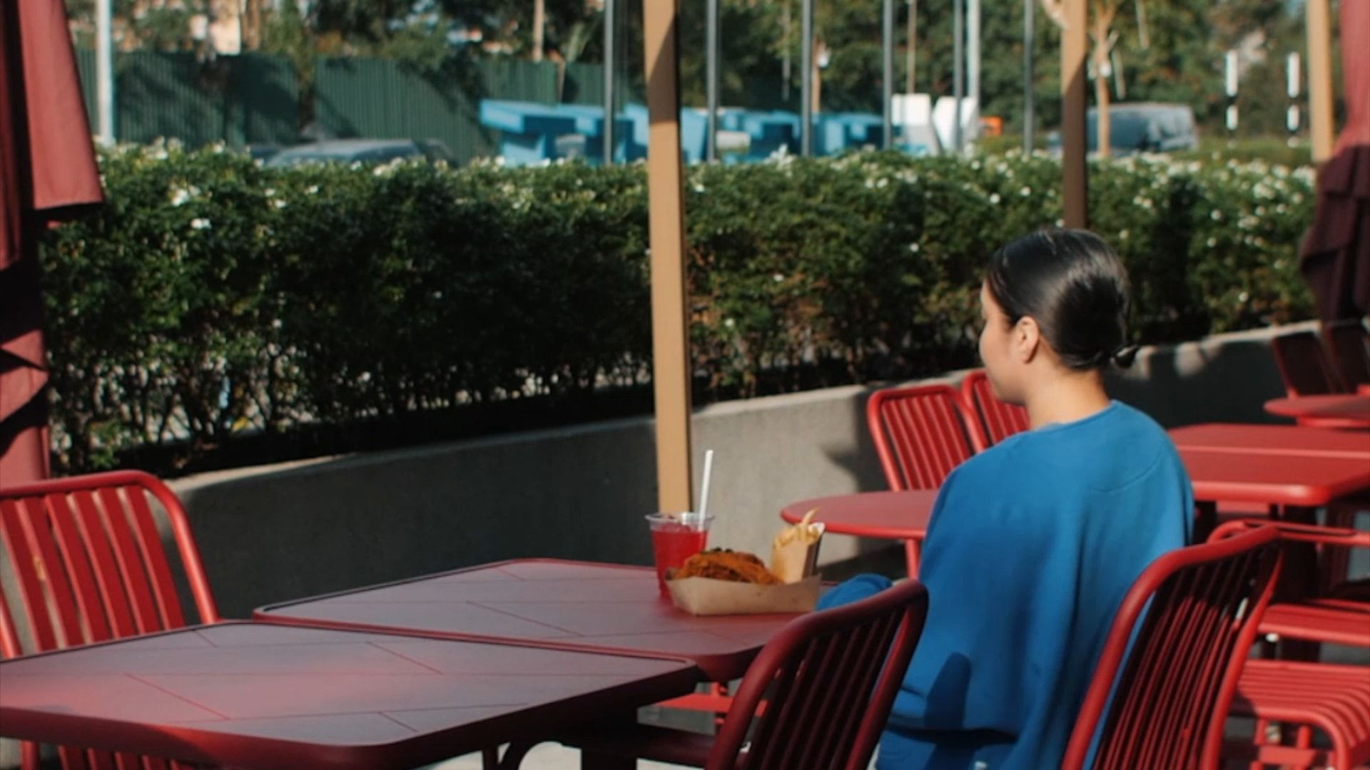 A guest setting her food down at a red table on The MET’s terrace, under the umbrellas and the tower